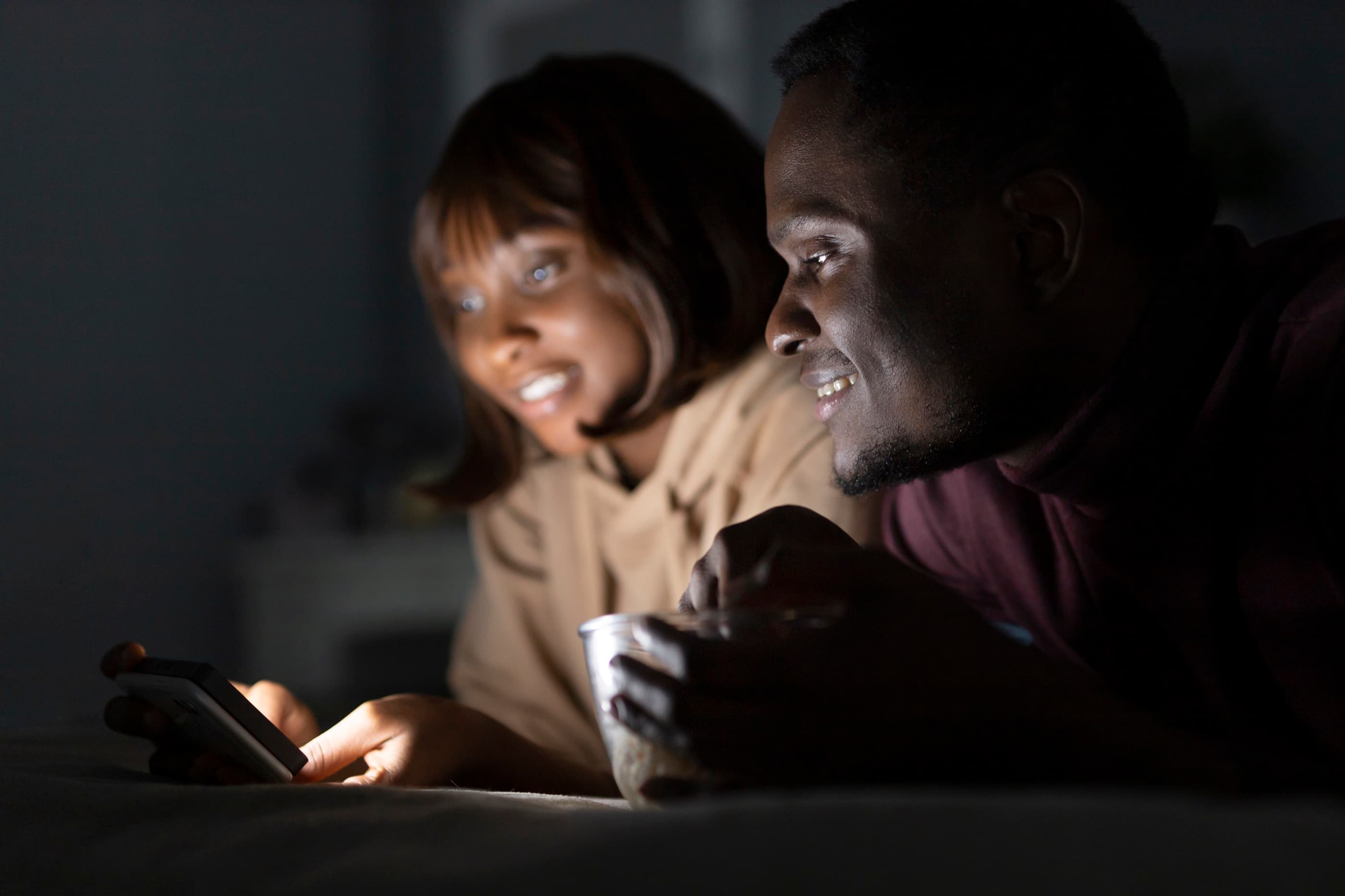 Two people smiling as they watch a screen together